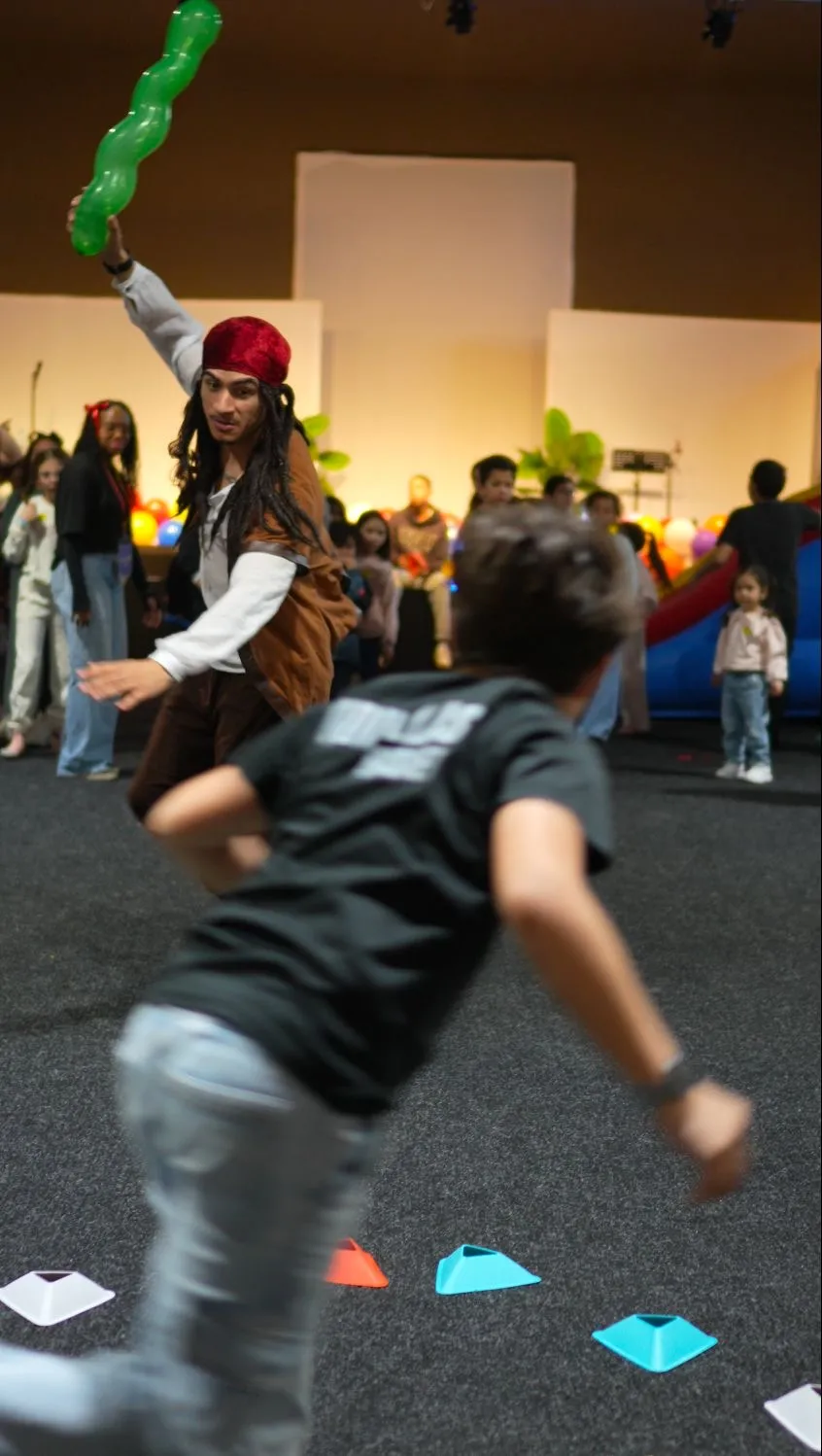 Ted vestido de pirata com balão, a orientar uma caça ao tesouro numa festa de aniversário