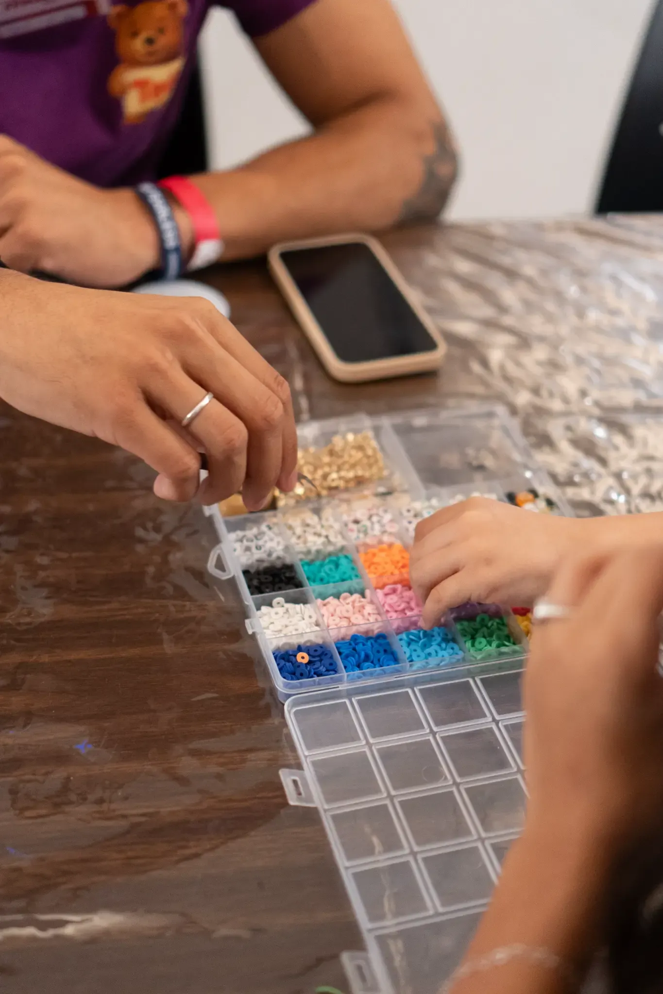 Mãos de criança a escolher contas coloridas para uma pulseira